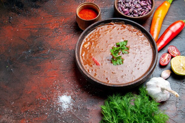 Tomatensuppe in einer braunen Schüssel und verschiedenen Gewürzen Knoblauchzitrone auf gemischter Farbtabelle