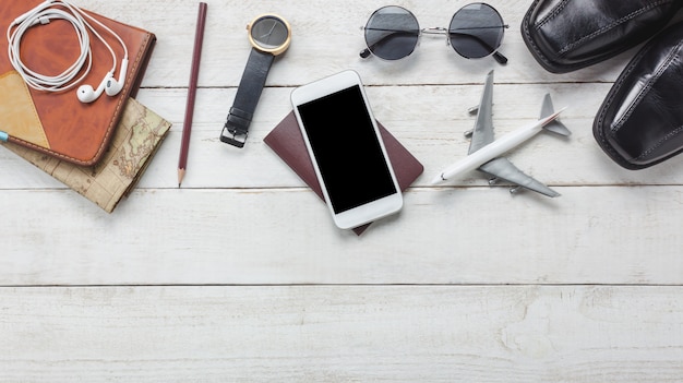 Top-Ansicht Zubehör zu Reisen concept.White Handy und Kopfhörer auf hölzernen background.airplane, Karte, Pass, Uhr auf Holz Tisch.