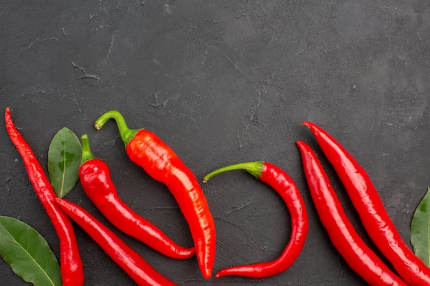 Top Close View rote Paprika und Pay Leaves auf schwarzem Tisch mit Kopierraum