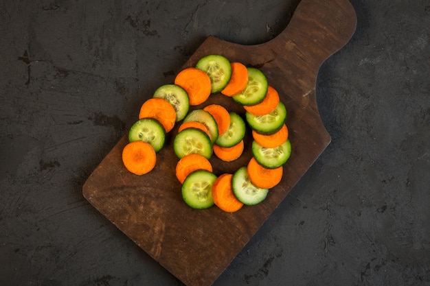 Top Karotten- und Gurkenscheiben auf Holzschneidebrett auf Schwarz