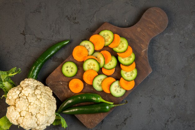 Top Karotten- und Gurkenscheiben und Blumenkohl auf Holzschneidebrett im Dunkeln