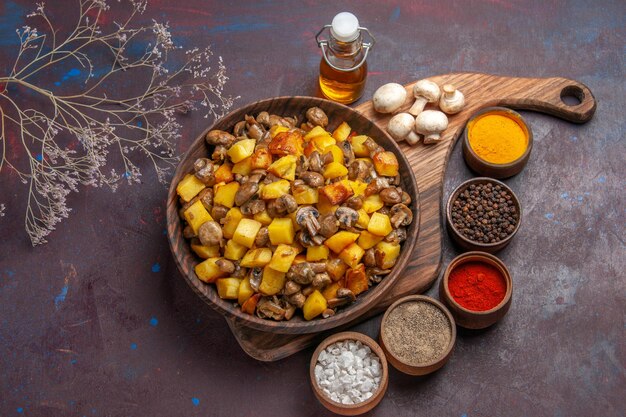 Top-Nahansicht-Teller mit Speiseteller mit Kartoffeln und Champignons, Champignonöl in der Flasche und bunten Gewürzen