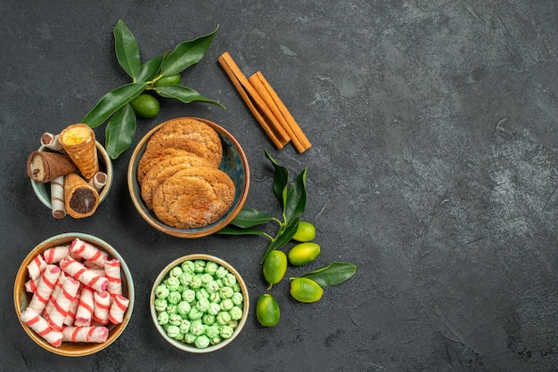 Top Nahaufnahme Ansicht Süßigkeiten Waffeln Kekse bunte Süßigkeiten Zimtstangen Zitrusfrüchte mit Blättern