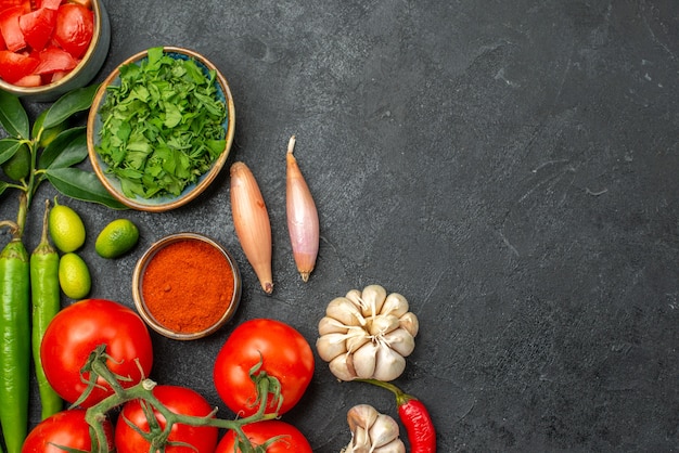 Top Nahaufnahme Ansicht Tomaten Zwiebeln Knoblauch Gewürze Kräuter Peperoni Tomaten auf dem dunklen Tisch