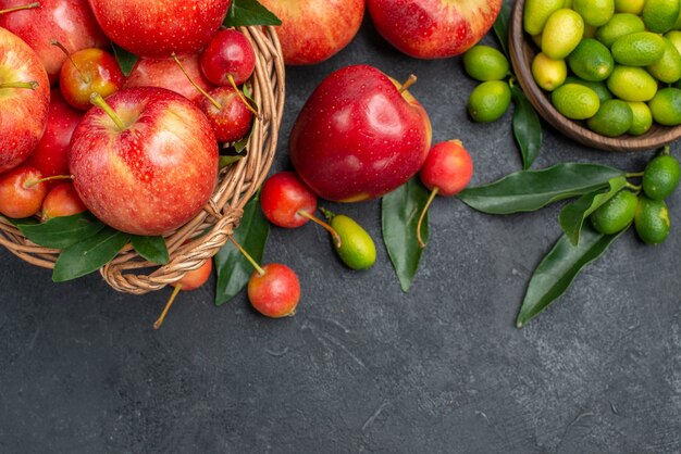 Top-Nahaufnahme Ansicht Zitrusfrüchte Mandarinen Kirschen Äpfel Zitrusfrüchte mit Blättern in der Schüssel