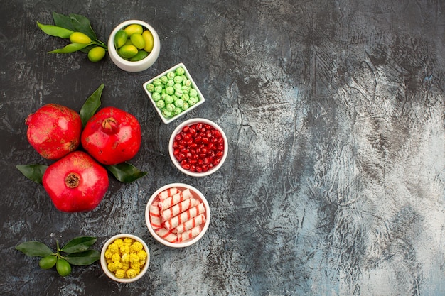 Top nahaufnahme bonbons die appetitlichen grün-weiß-gelben bonbons limetten und drei granatäpfel