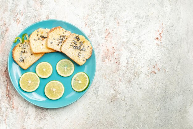 Top Nahaufnahme Brot und Zitrone in Scheiben geschnittene Zitrusfrüchte und Weißbrot in der Platte auf der linken Seite des Tisches