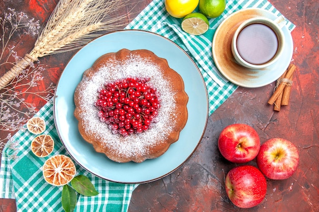 Top Nahaufnahme einen Kuchen eine Tasse Tee Zimt Äpfel Kuchen Zitrusfrüchte auf der Tischdecke