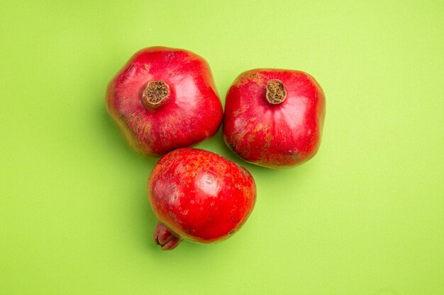 Top Nahaufnahme Granatäpfel drei rote Granatäpfel auf dem grünen Tisch