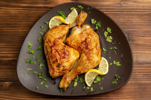 Top Nahaufnahme Hähnchen mit Kräutern Hähnchenschenkel mit Kräutern und Zitrone in der braunen Platte in der Mitte des Tisches