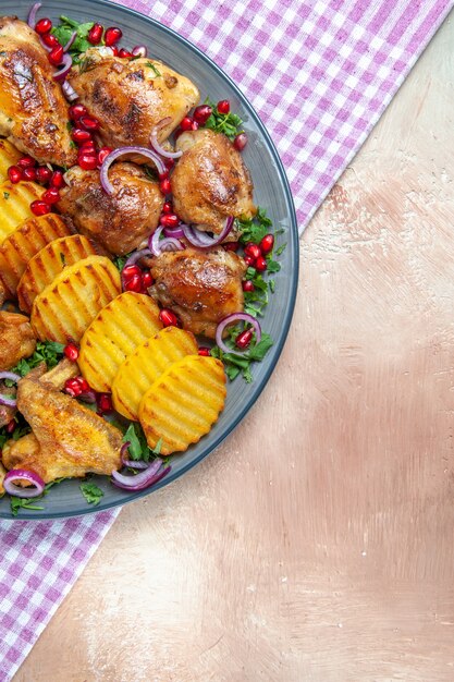 Top Nahaufnahme Huhn die appetitlichen Hühnchen Kartoffeln Kräuter Zwiebel auf der karierten Tischdecke