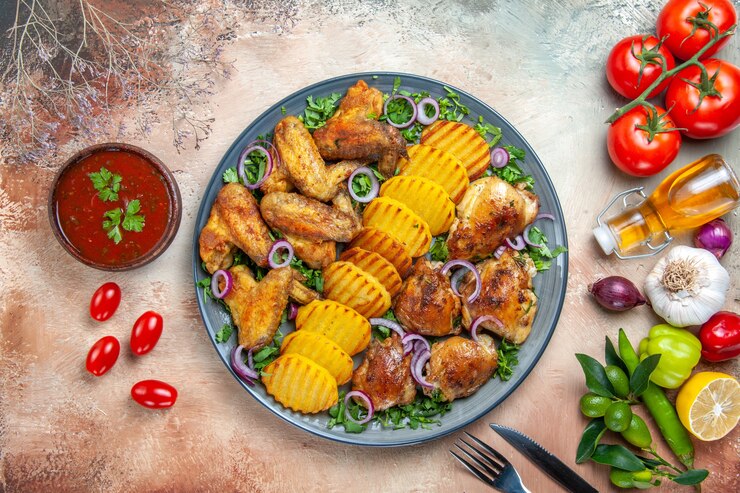 Kostenlose Foto top nahaufnahme huhn hühnerflügel kartoffeln zwiebel kräuter gemüse sauce gabel messer