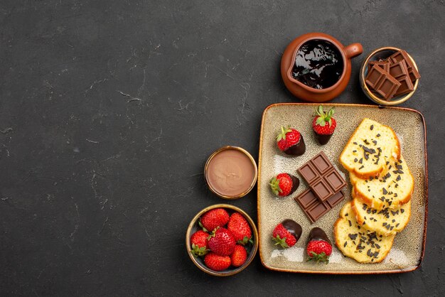 Top Nahaufnahme Kuchen mit Erdbeerschokolade und Erdbeere in braunen Schalen und Kuchenteller mit schokoladenüberzogenen Erdbeeren auf der rechten Seite des Tisches