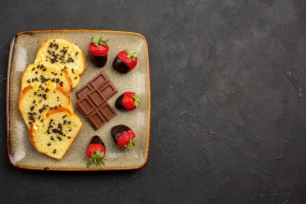 Top Nahaufnahme Kuchenstücke appetitliche Kuchenstücke mit Schokolade und Erdbeeren auf der linken Seite des dunklen Tisches