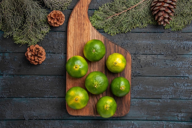 Kostenloses Foto top nahaufnahme limetten und zweige limetten auf dem küchenbrett neben den ästen und zapfen