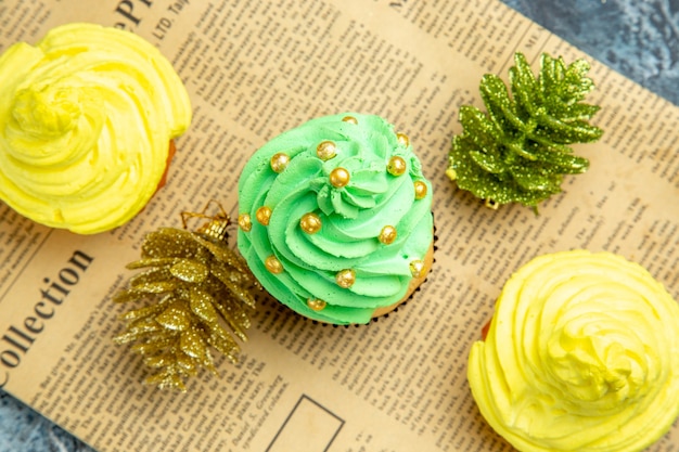 Top Nahaufnahme Mini Cupcakes Weihnachtsschmuck auf Zeitung auf dunklem Hintergrund