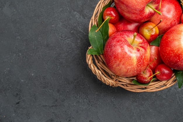 Top Nahaufnahme Obst Äpfel und Beeren im Korb auf dem dunklen Tisch