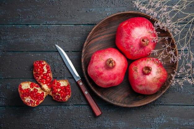 Top Nahaufnahme Schüssel Granatäpfel Schüssel Granatäpfel neben Messer pilled Granatapfel und Ästen