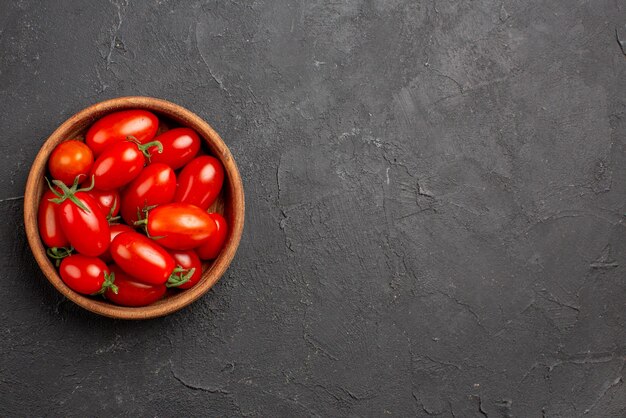 Top Nahaufnahme Tomaten in Schüssel reife rote Tomaten in Schüssel auf der linken Seite des dunklen Tisches