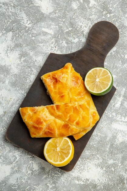Top Nahaufnahme Torten und Zitronen Torten Limette und Zitrone auf dem dunklen Holzbrett auf grauem Hintergrund