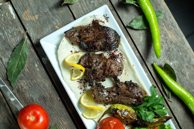 Top-Rindfleisch-Kebab, serviert mit Zwiebeln, gegrillter Tomate und Pfeffer auf einer Platte