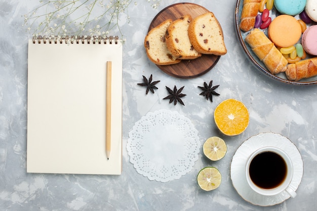 Top vie französische Macarons mit Bagels und einer Tasse Tee auf Weiß