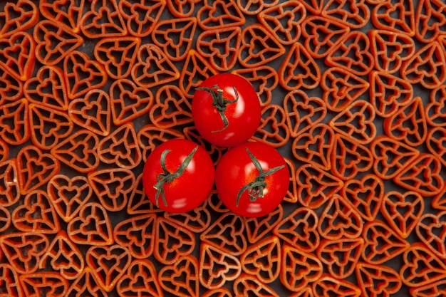 Top View Tomaten auf roten Herzen italienische Pasta auf dunklem Tisch