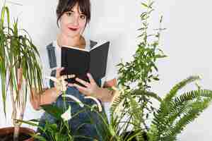 Kostenloses Foto topfpflanzen vor dem schönen weiblichen floristen, der tagebuch hält