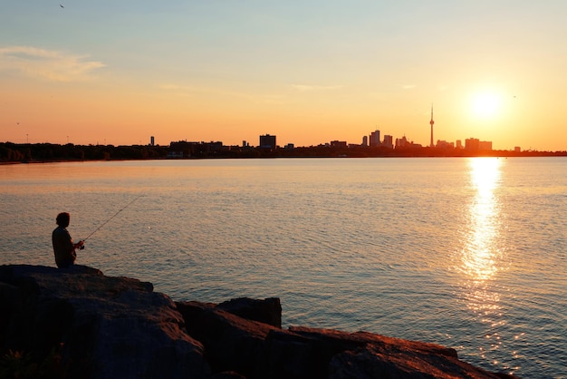 Toronto-Sonnenaufgangschattenbild über See mit Mannfischen.