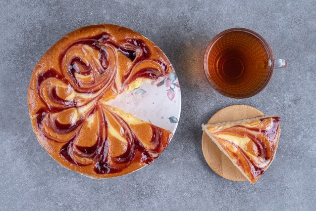 Torte mit Beeren und Tasse Tee auf Marmoroberfläche