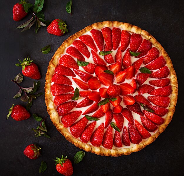 Torte mit Erdbeeren und Schlagsahne, dekoriert mit Minzblättern. Draufsicht