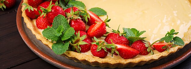 Torte mit Erdbeeren und Schlagsahne, dekoriert mit Minzblättern