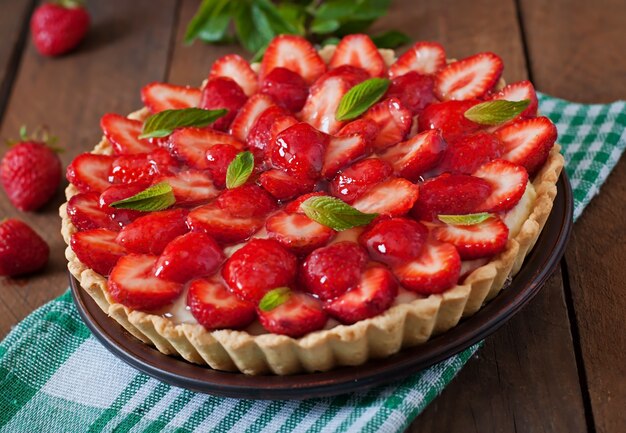 Torte mit Erdbeeren und Schlagsahne, dekoriert mit Minzblättern