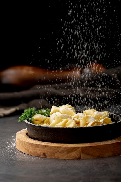 Tortellini in der dunklen metallischen Platte auf einem hölzernen Stand