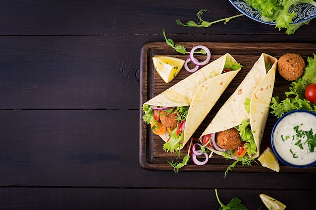 Tortillaverpackung mit Falafel und frischem Salat. Vegane Tacos. Vegetarisch gesundes Essen. Ansicht von oben