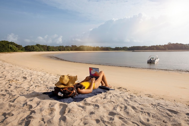 Totale Frau, die mit Laptop am Strand arbeitet