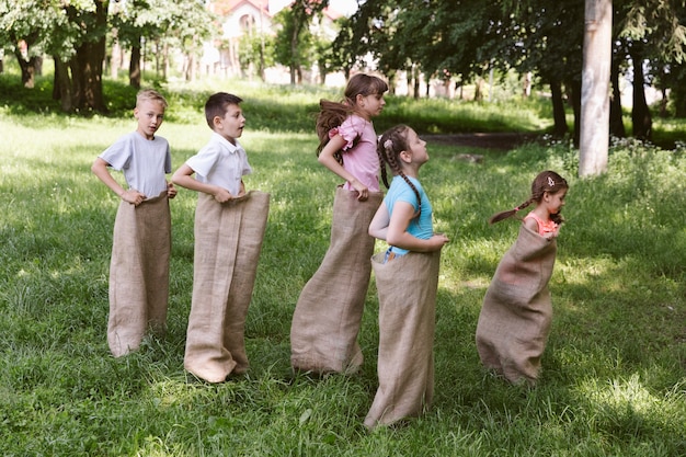 Totale Mädchen und Jungen, die in Leinensäcken laufen