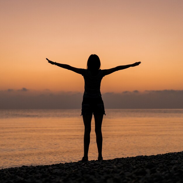 Tourist bei Sonnenaufgang hält ihre Hände in der Luft