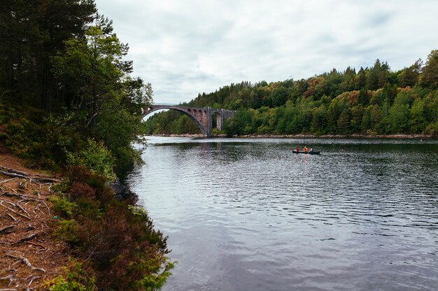 Tourist, der das Boot auf dem See mit grüner Landschaft rudert