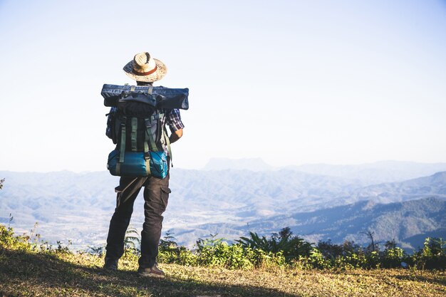 Tourist vom Berggipfel. Sonnenstrahlen. Mann tragen großen Rucksack gegen Sonnenlicht