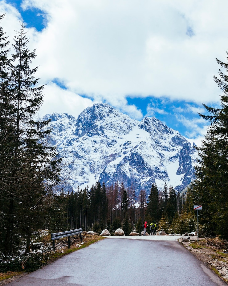 Kostenlose Foto tourist zwei, der auf straße nahe dem schneebedeckten berg steht