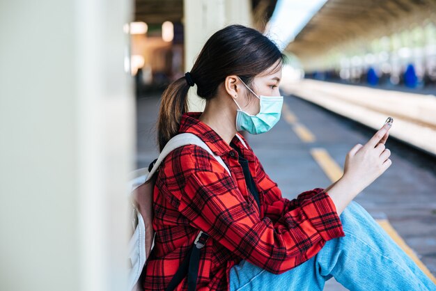 Touristen sitzen und beobachten Telefone auf dem Fußweg neben der Eisenbahn.