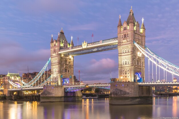 Tower Bridge, umgeben von Gebäuden und Lichtern am Abend in London, Großbritannien