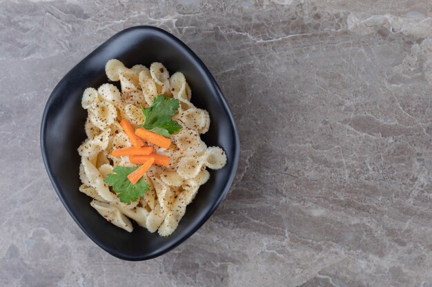 Traditionelle italienische Pasta mit fein gehackter Karotte und grünem Gemüse, auf dem Marmor.