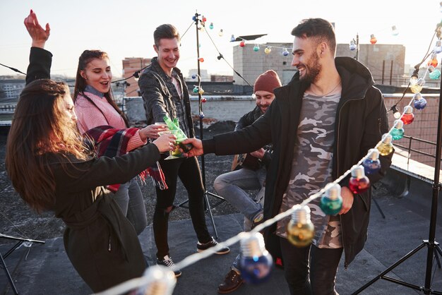 Traditionelle Klopfbrille. Überall auf dem Dach, wo sich eine junge Gruppe von Freunden befindet, haben Glühbirnen beschlossen, ihr Wochenende mit Gitarre und Alkohol zu verbringen