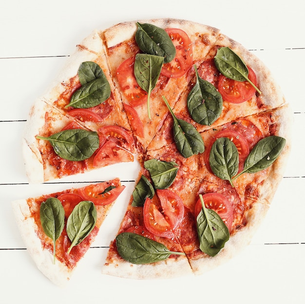 Traditionelle Pizza mit Tomatenscheiben und Basilikumblättern