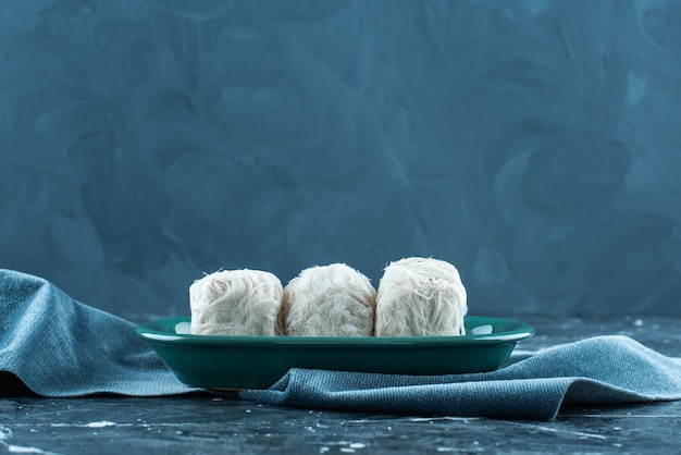 Traditionelle türkische Zuckerwatte auf einem Teller auf einem Handtuch, auf dem blauen Hintergrund.