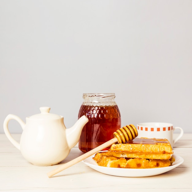 Traditionelle weiche frische Waffeln Belgiens mit einem Honig und einer Teekanne auf Tabelle