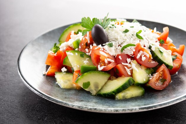 Traditioneller bulgarischer Shopska-Salat mit Tomatengurke und bulgarischem Sirene-Käse auf schwarzem Schieferhintergrund