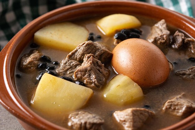 Traditioneller jüdischer Cholent in Schüssel auf Holztisch